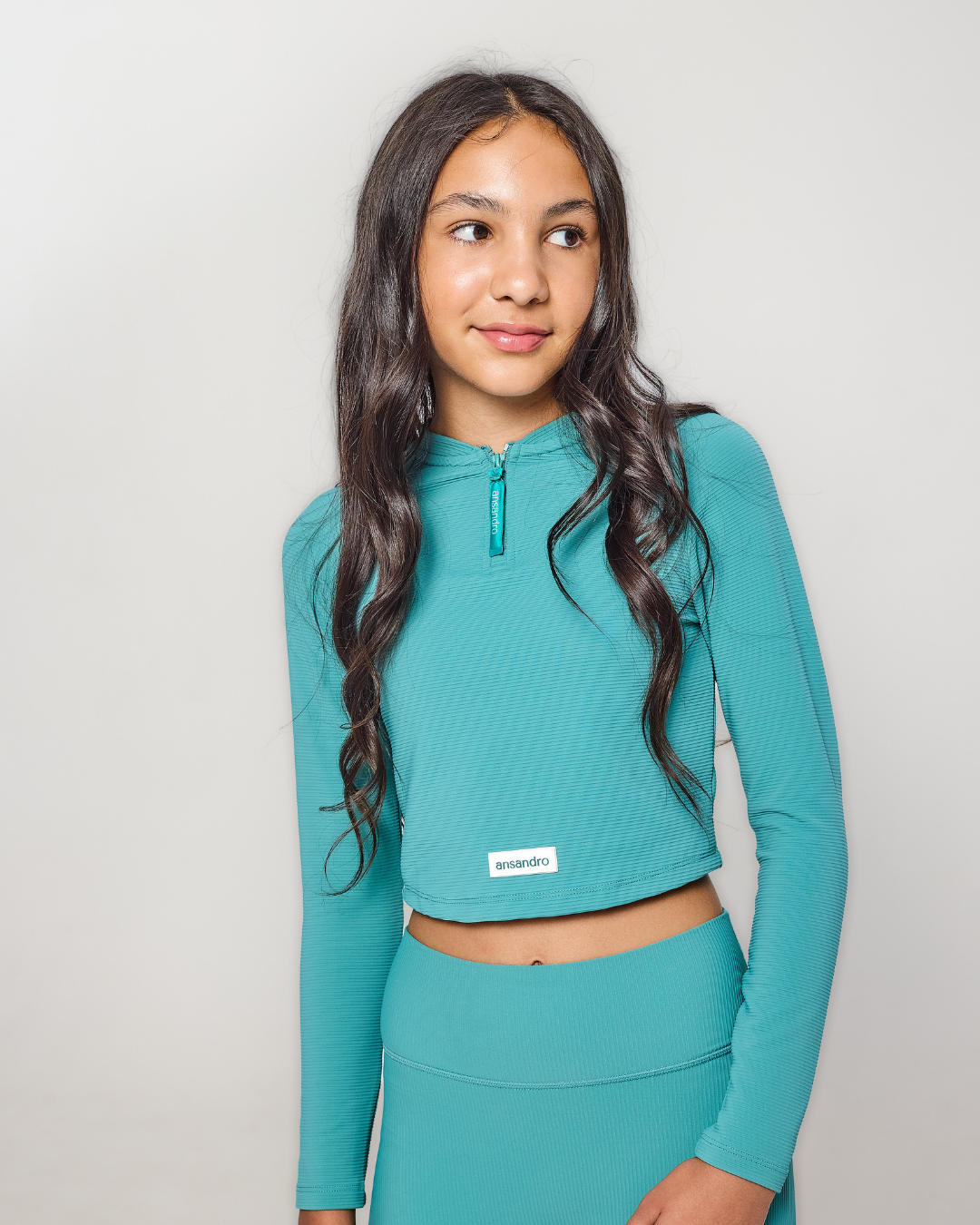 Woman wearing a teal athletic outfit on a plain background