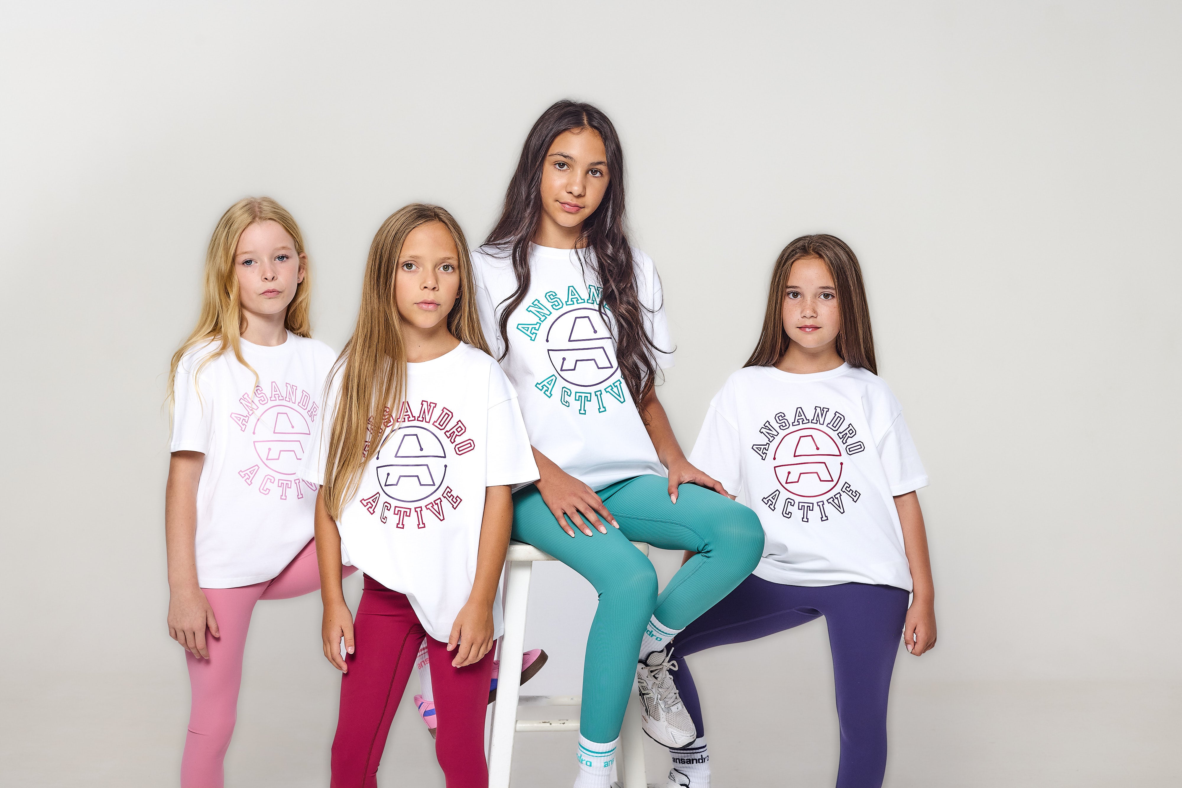 Four young girls wearing 'Aeropostale' branded t-shirts and leggings on a plain background