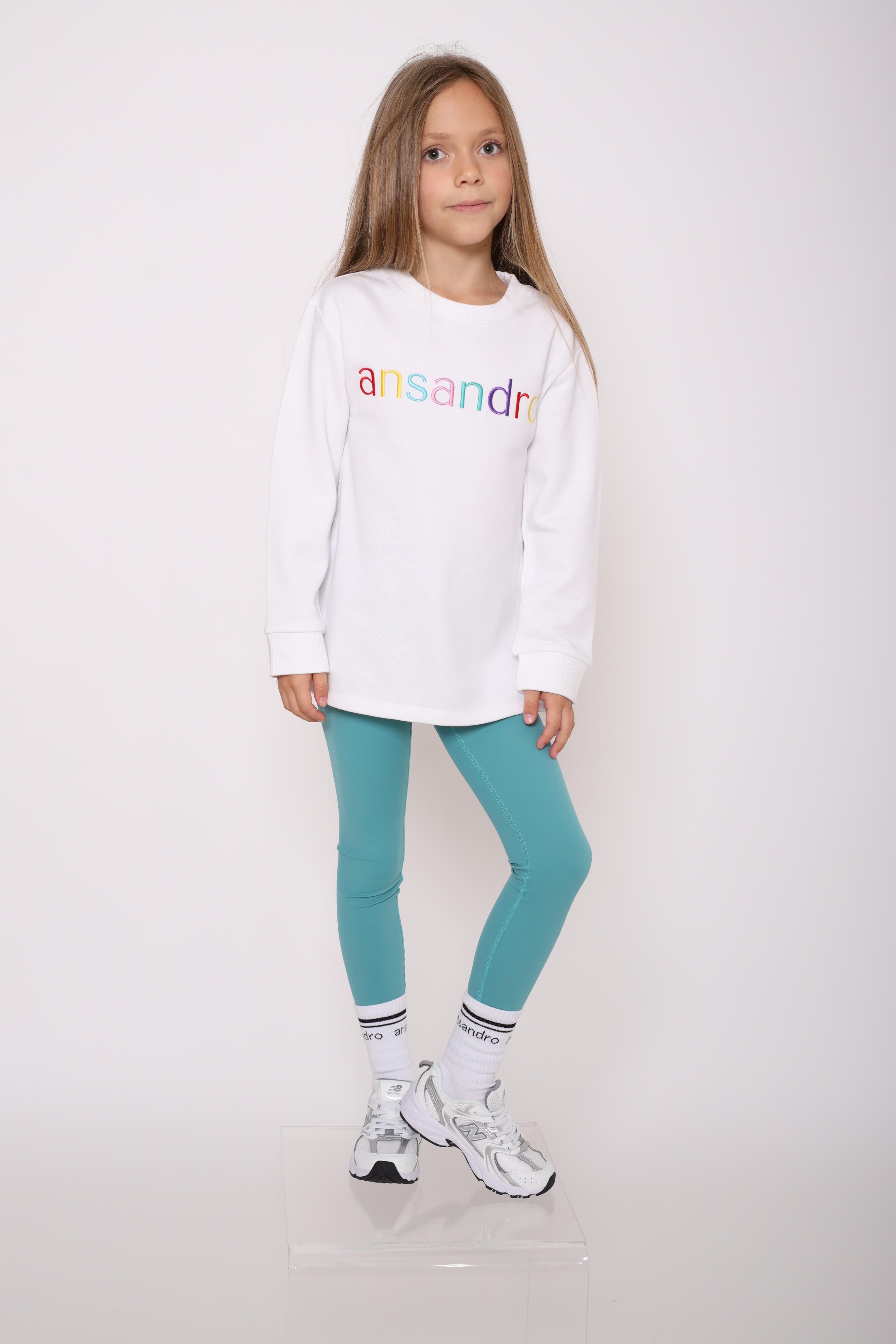 100% cotton branded socks for kids - soft, breathable, and durable design. Black text and black banding paired with girls teal high-waisted leggings and 100% cotton white sweatshirt