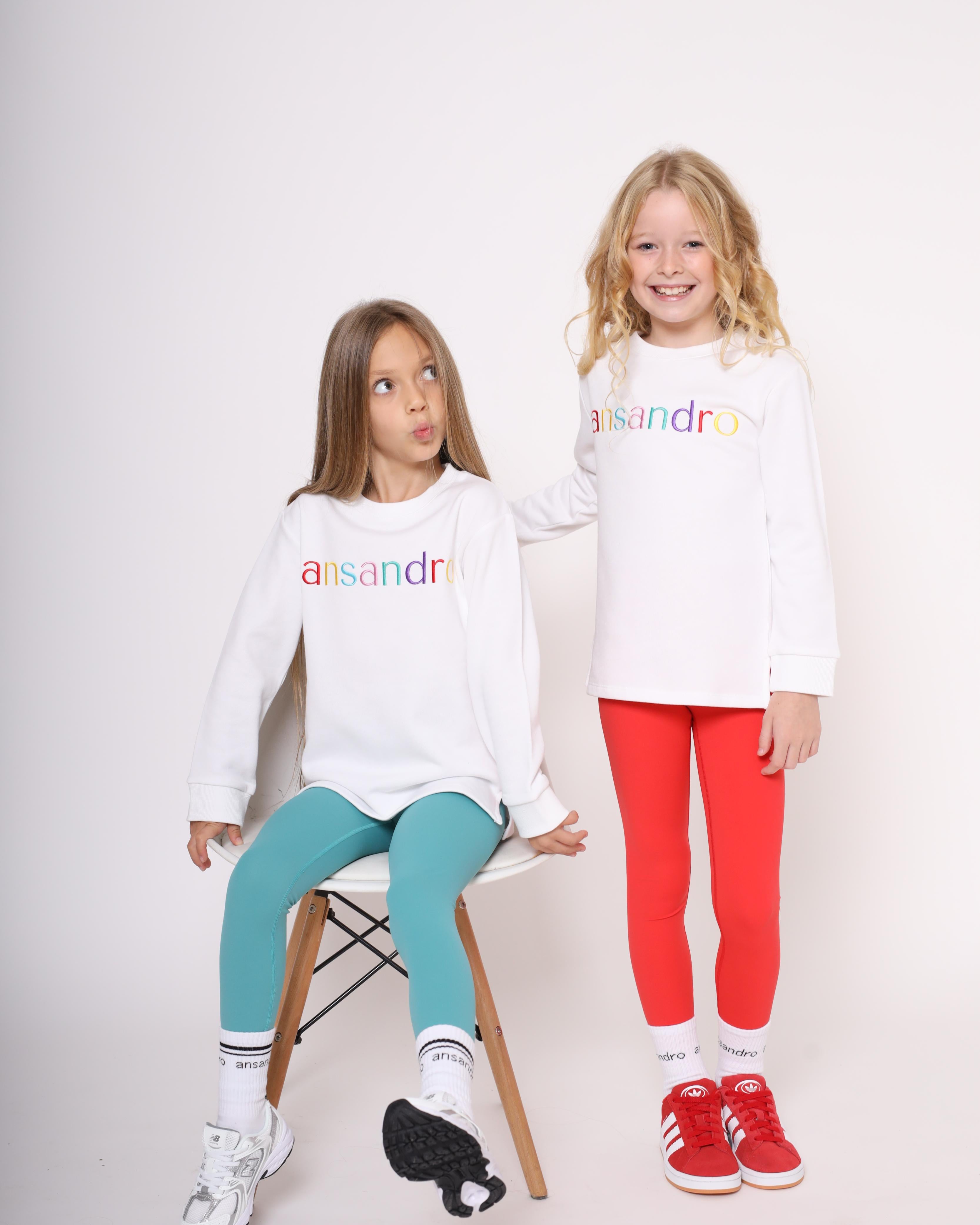 White lightweight sweatshirt for kids - 100% cotton with colourful embroidered branding paired with red and teal girls high-waisted leggings with branded socks
