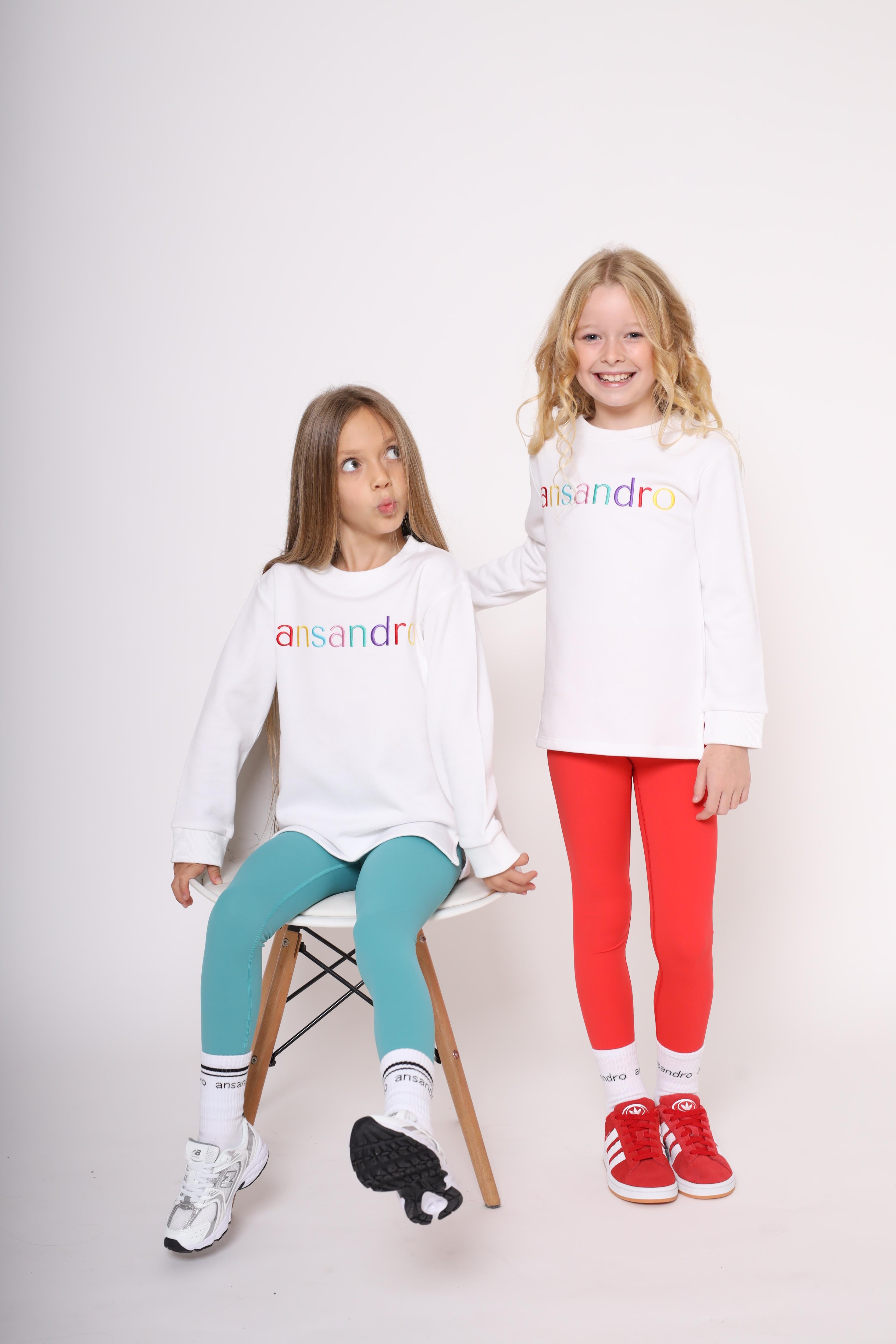 White lightweight sweatshirt for kids - 100% cotton with colourful embroidered branding paired with red and teal girls high-waisted leggings with branded socks