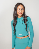Woman wearing a teal athletic outfit on a plain background