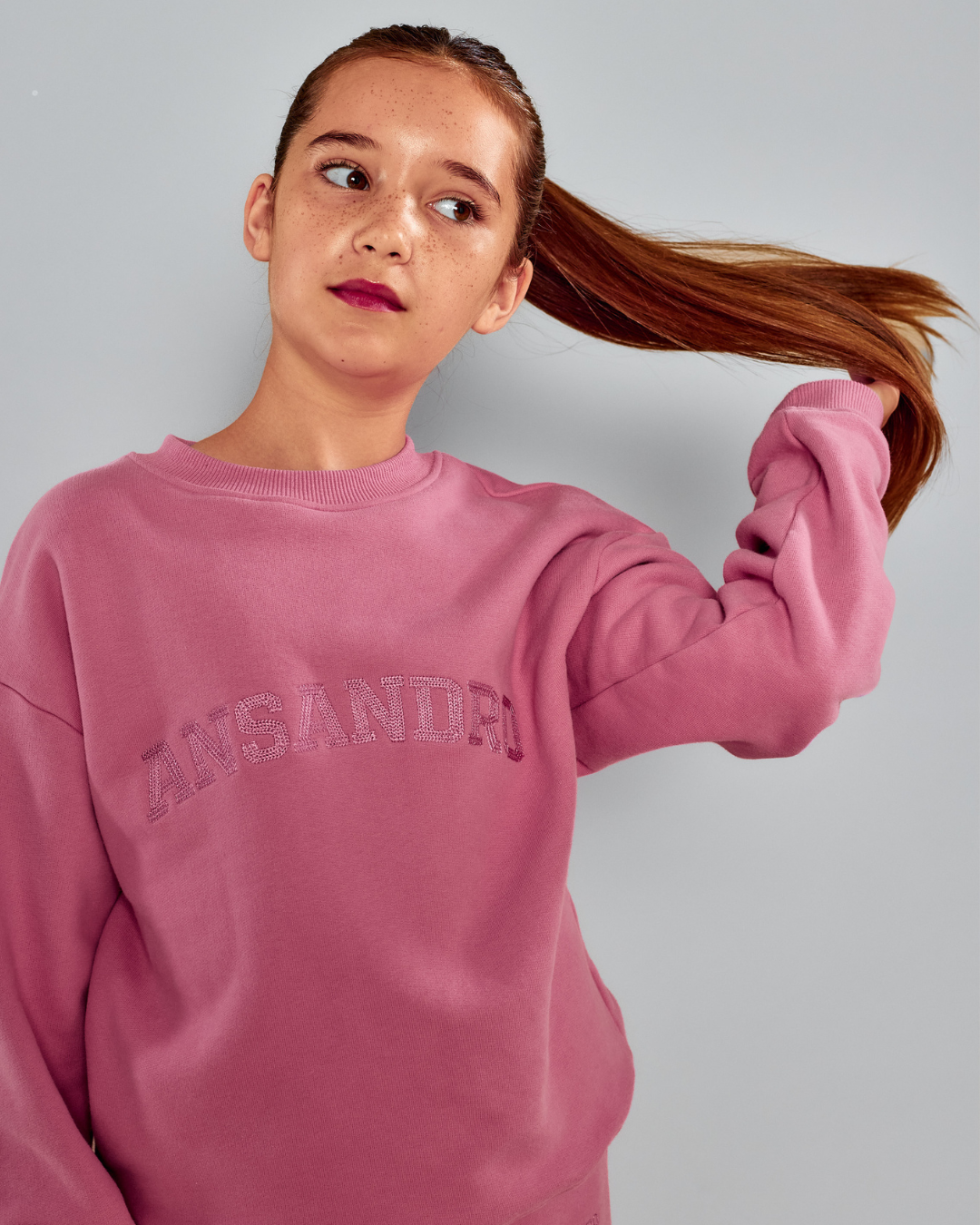 Girl wearing the Ansandro Kids blush 100% cotton sweatshirt with tonal embroidered logo.
