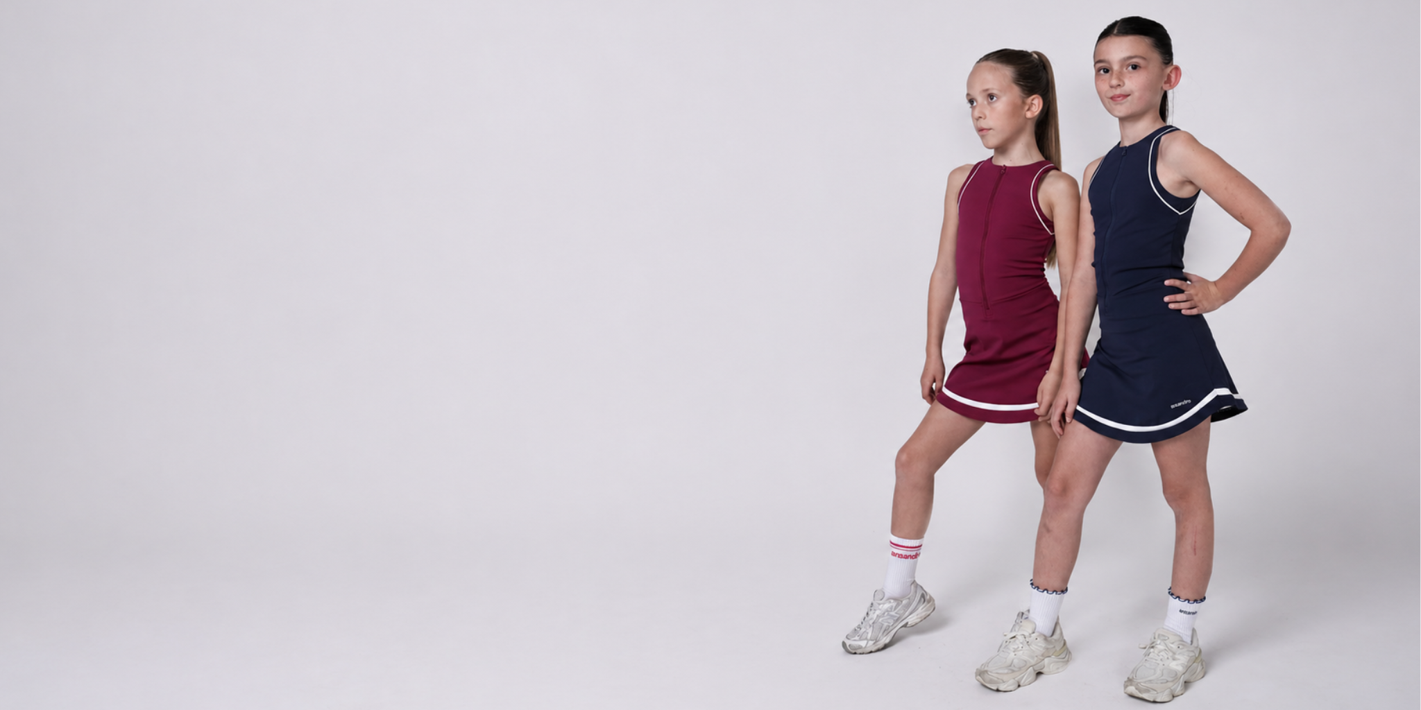 Two young girls wearing athletic outfits on a white background