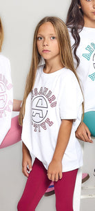 Girl wearing a white oversized t-shirt with a logo and red leggings on a light background