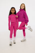 Two children wearing matching pink tracksuits on a white background