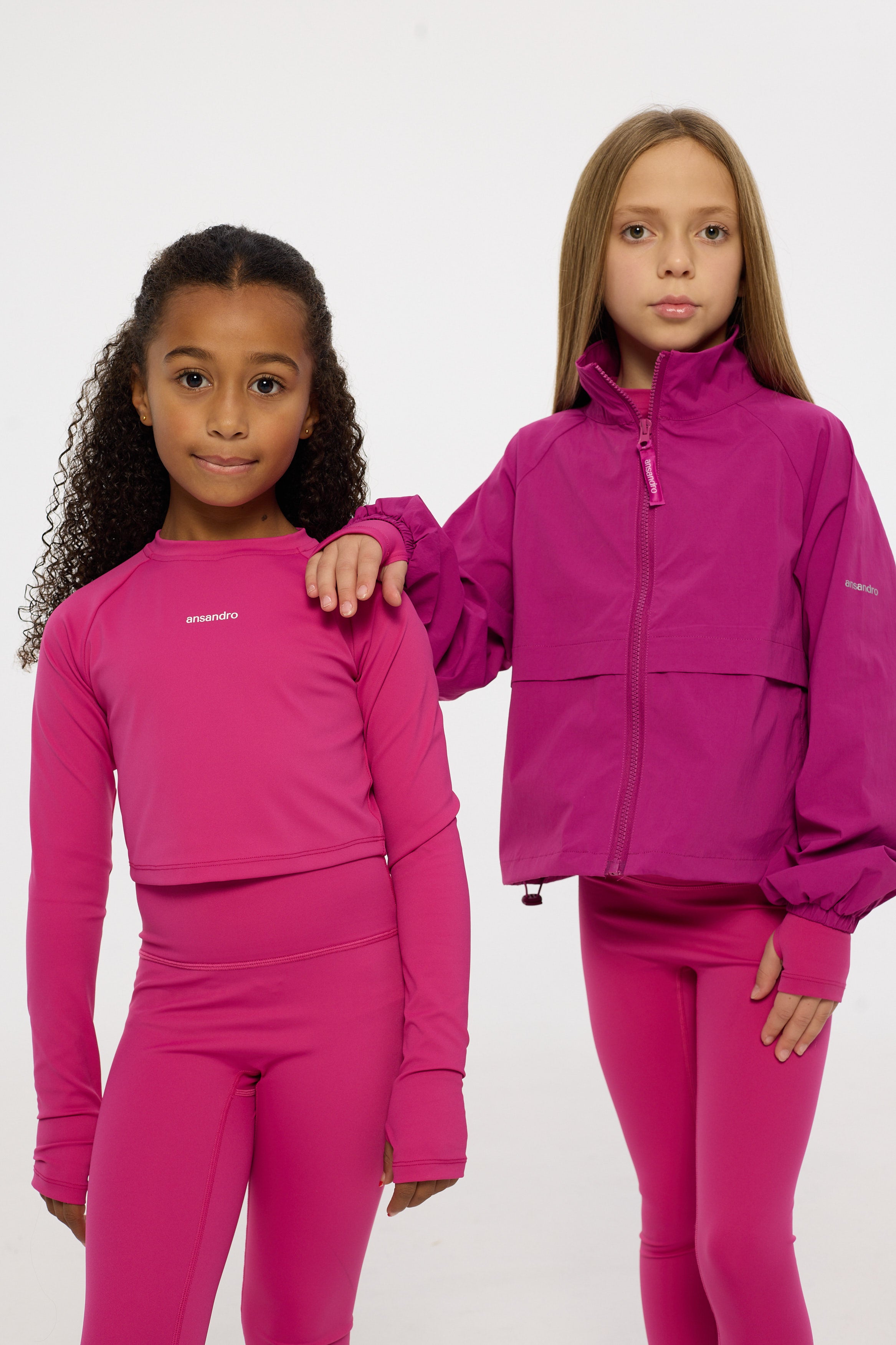 Two children wearing matching pink outfits on a white background