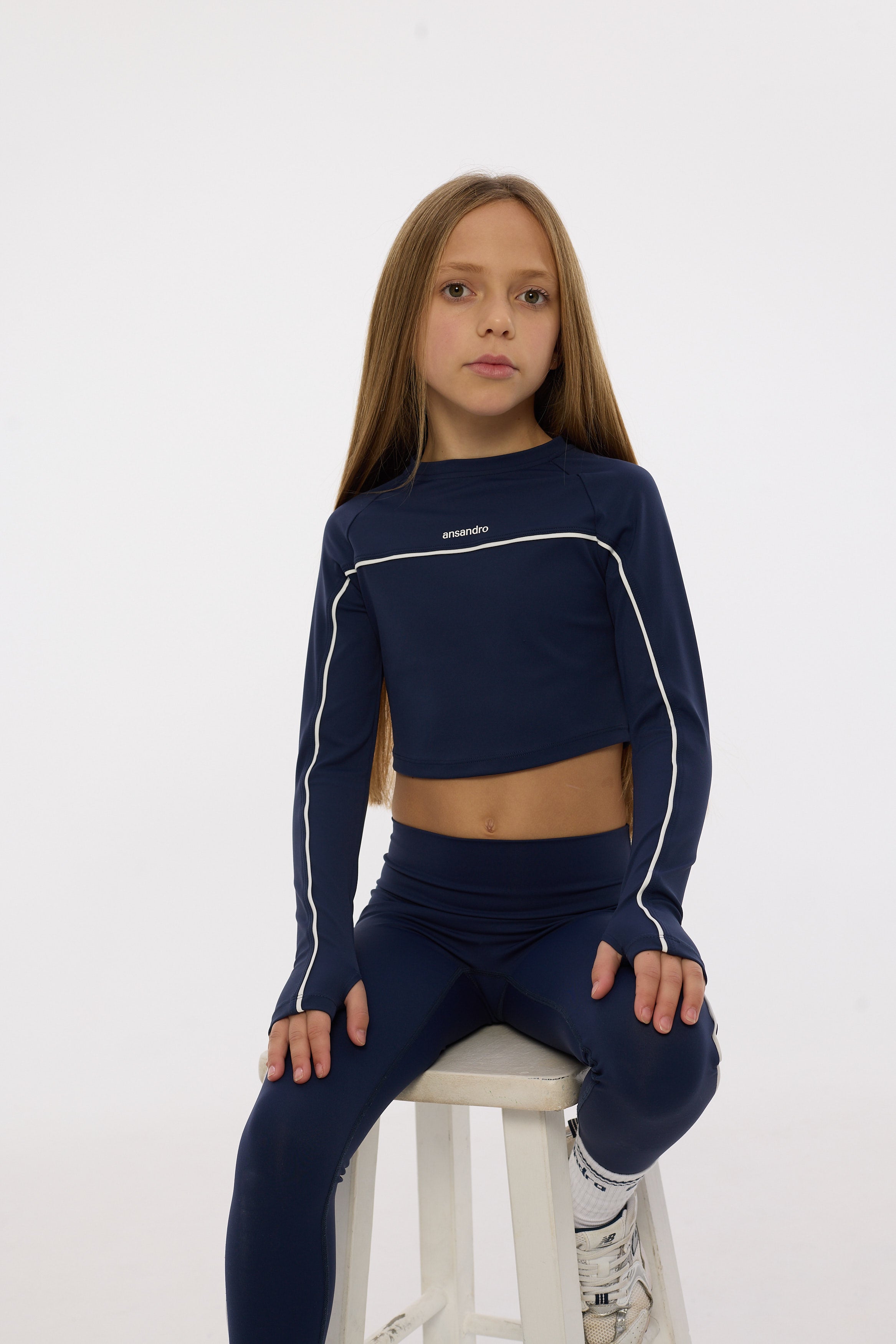 Girl wearing a navy blue athletic outfit with white accents on a white background
