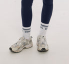 Young girl wearing a white t-shirt with text and dark leggings on a white background