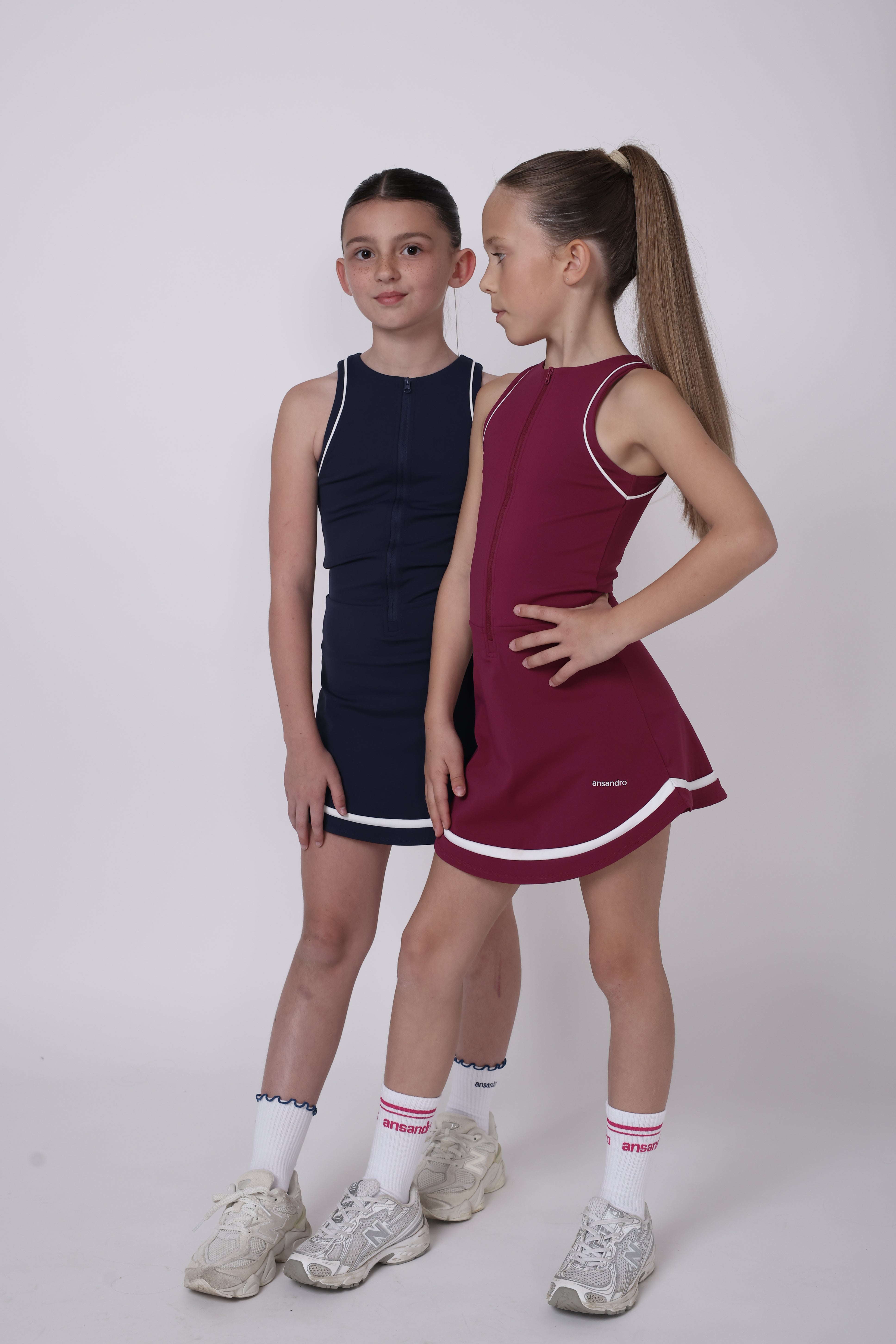 Two children in sports uniforms standing side by side on a plain background by ansandro